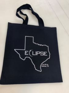 black tote bag with solar eclipse logo in white