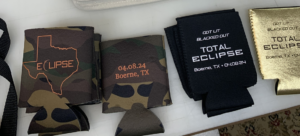 solar eclipse koozies in camo, black, and metallic gold